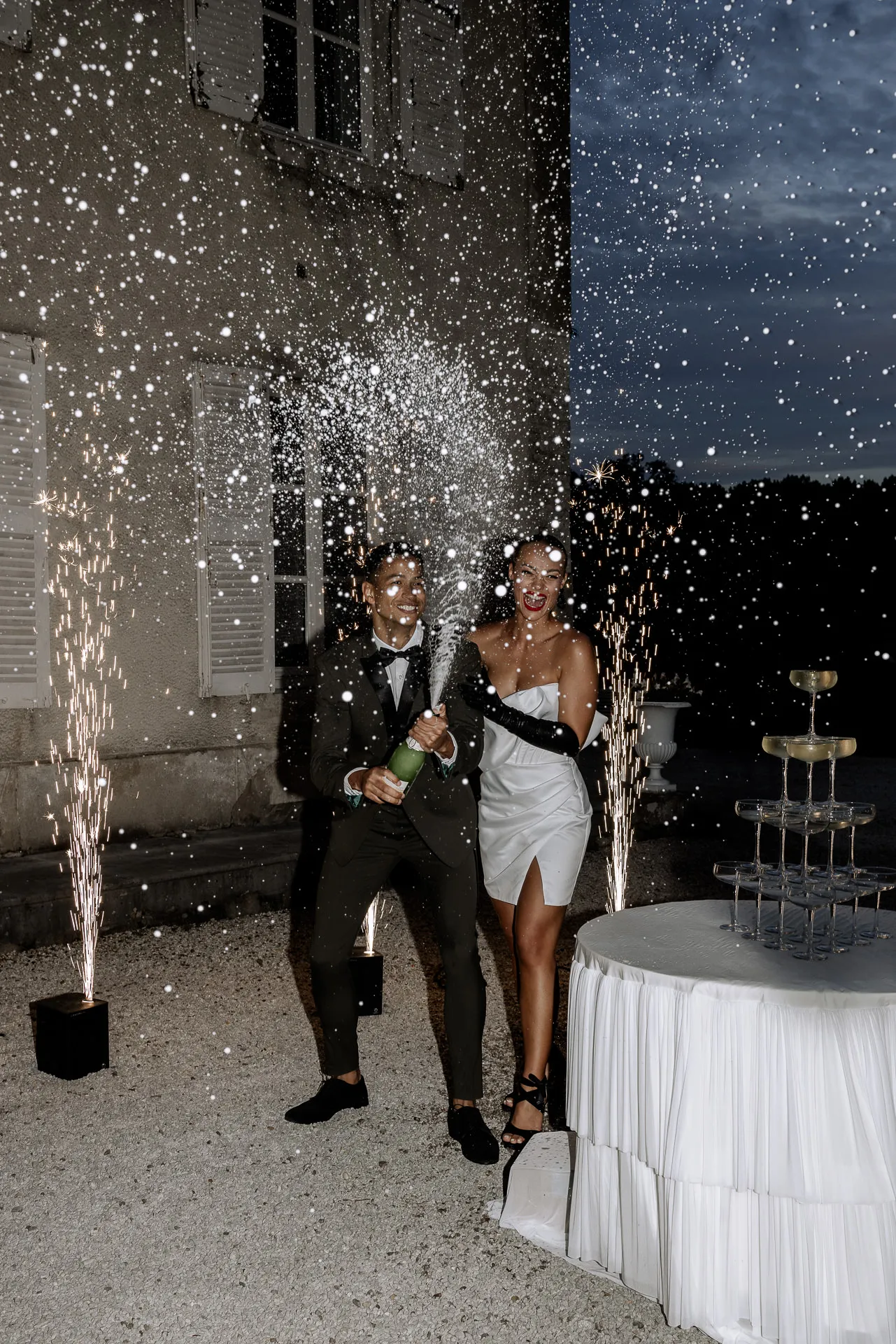 Bridal couple celebrating exuberantly with champagne fountains and fireworks at Chateau de Varennes in France